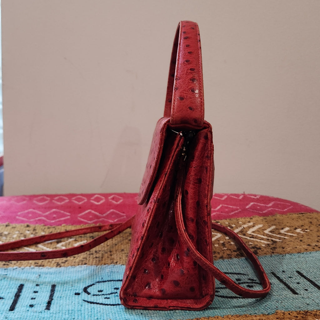Side profile of vintage Mike's Collection red ostrich-embossed leather mini handbag, showing gusset, zip and structured depth