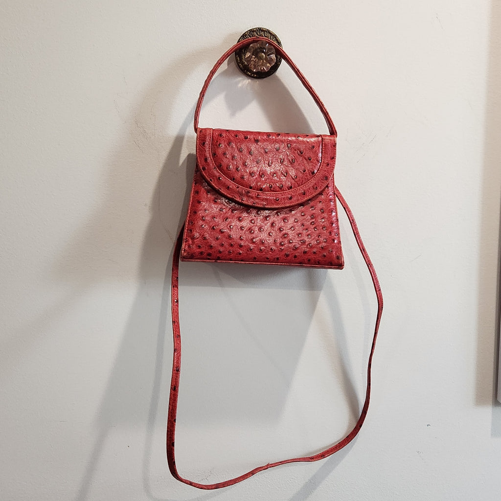 Front view of vintage Mike's Collection red ostrich-embossed leather mini handbag hanging, with top handle and longer strap