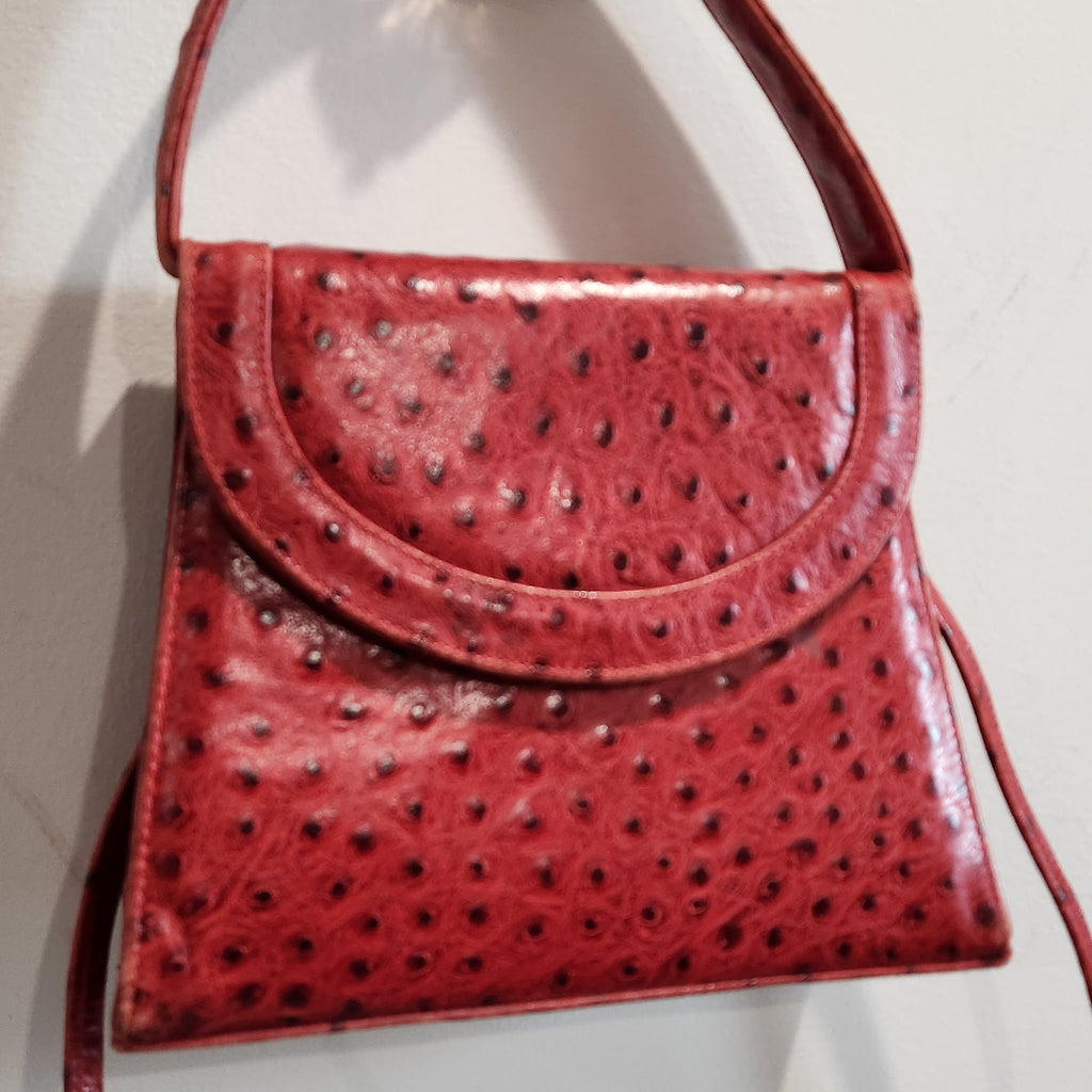 Close-up of the rounded flap of vintage Mike's Collection red ostrich-embossed leather mini handbag, showing texture