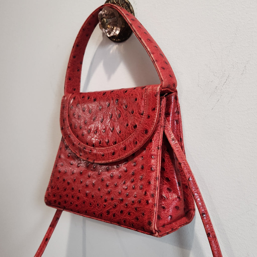 Back view of vintage Mike's Collection red ostrich-embossed leather mini handbag hanging, with card in the slip pocket