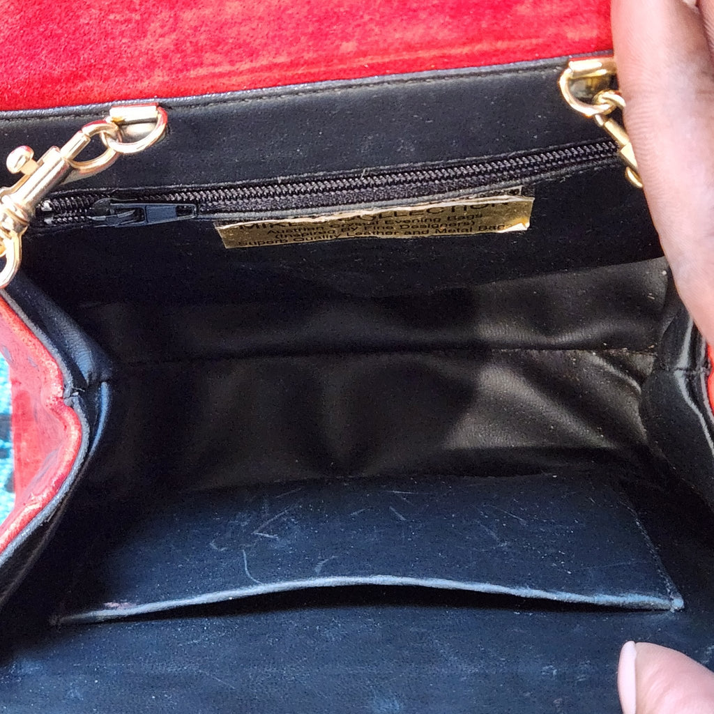 Interior of vintage Mike's Collection red ostrich-embossed leather mini handbag, showing black vinyl lining, zippered compartment, slip pocket and designer label