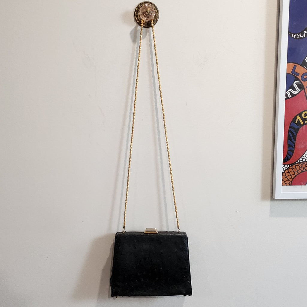 Full view of vintage Beoni Lucia black ostrich-textured leather evening bag hanging by its braided gold chain strap