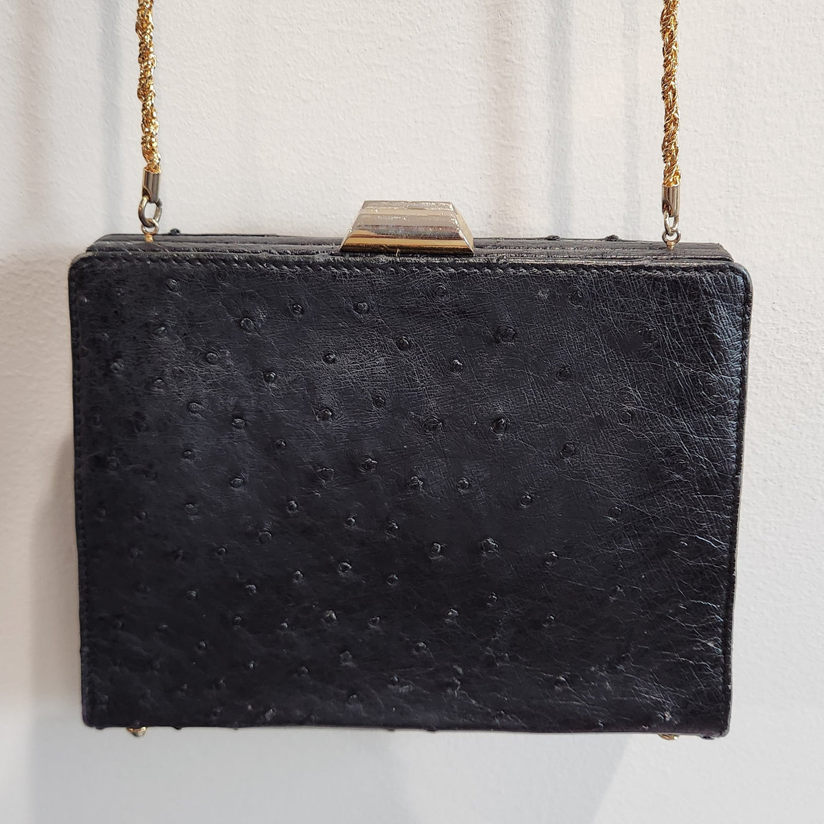 Front view of vintage Beoni Lucia black ostrich-textured leather evening bag with gold-tone geometric frame clasp and braided gold chain strap