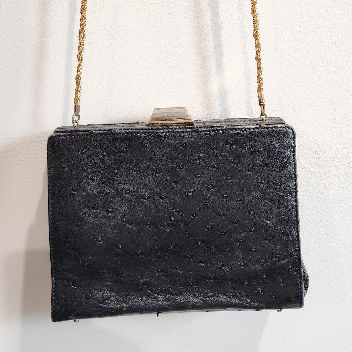 Front view of vintage Beoni Lucia black ostrich-textured leather evening bag with braided gold chain strap draped across the front