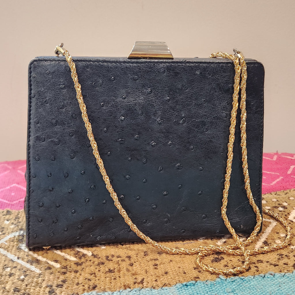 Front view of vintage Beoni Lucia black ostrich-textured leather evening bag with braided gold chain strap draped diagonally