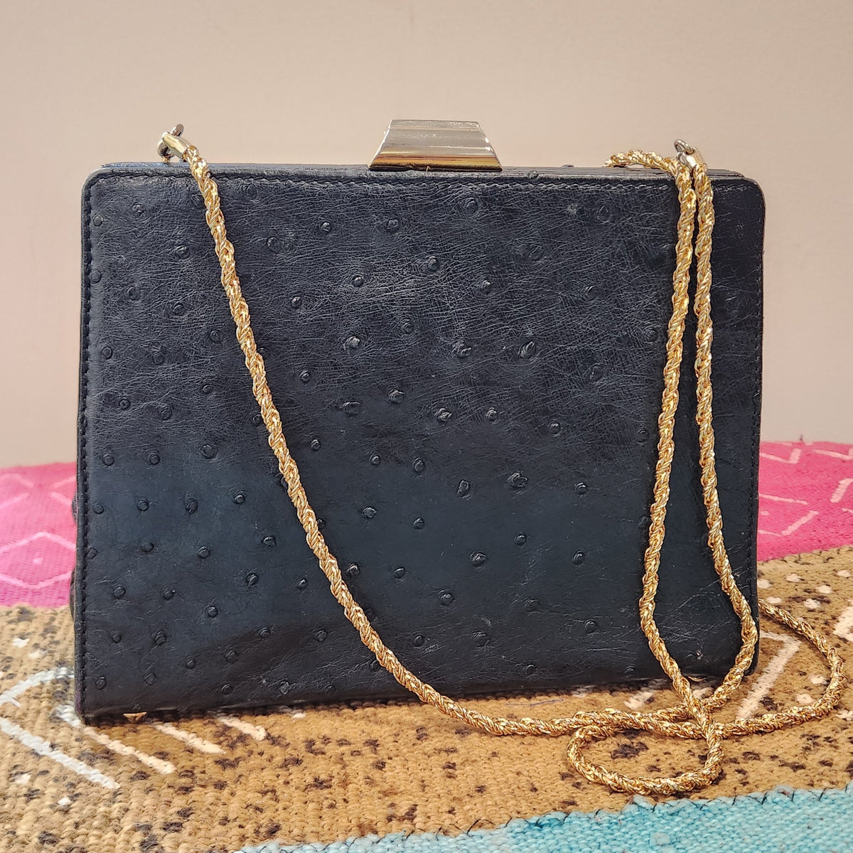 Front view of vintage Beoni Lucia black ostrich-textured leather evening bag with braided gold chain strap draped diagonally