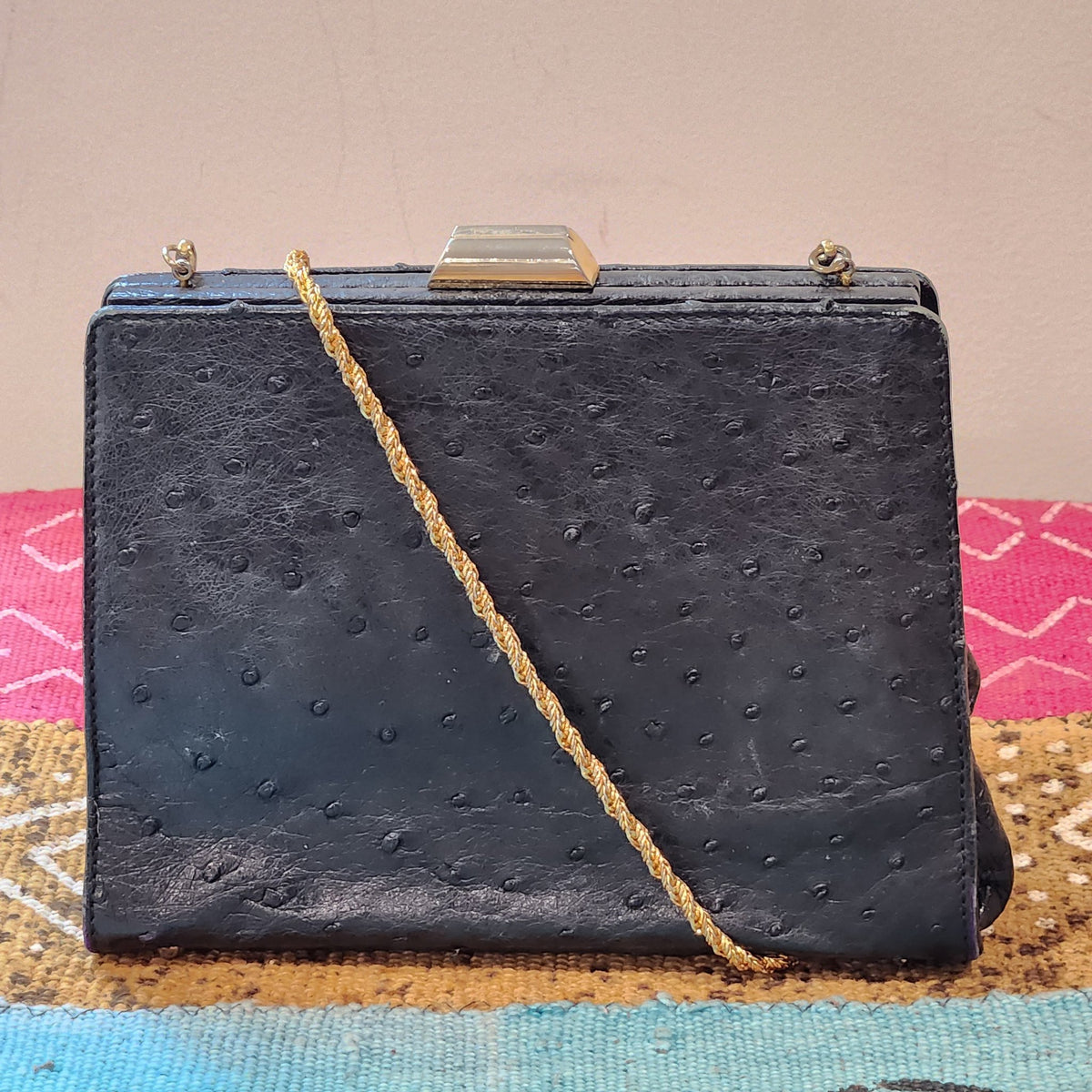 Front view of vintage Beoni Lucia black ostrich-textured leather evening bag with braided gold chain strap draped across the body