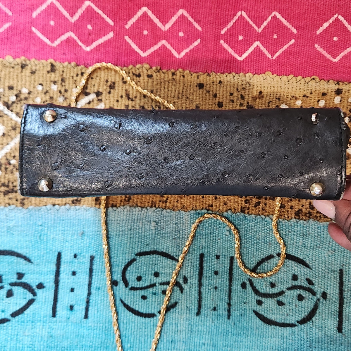 Base view of vintage Beoni Lucia black ostrich-textured leather evening bag, showing four protective metal feet