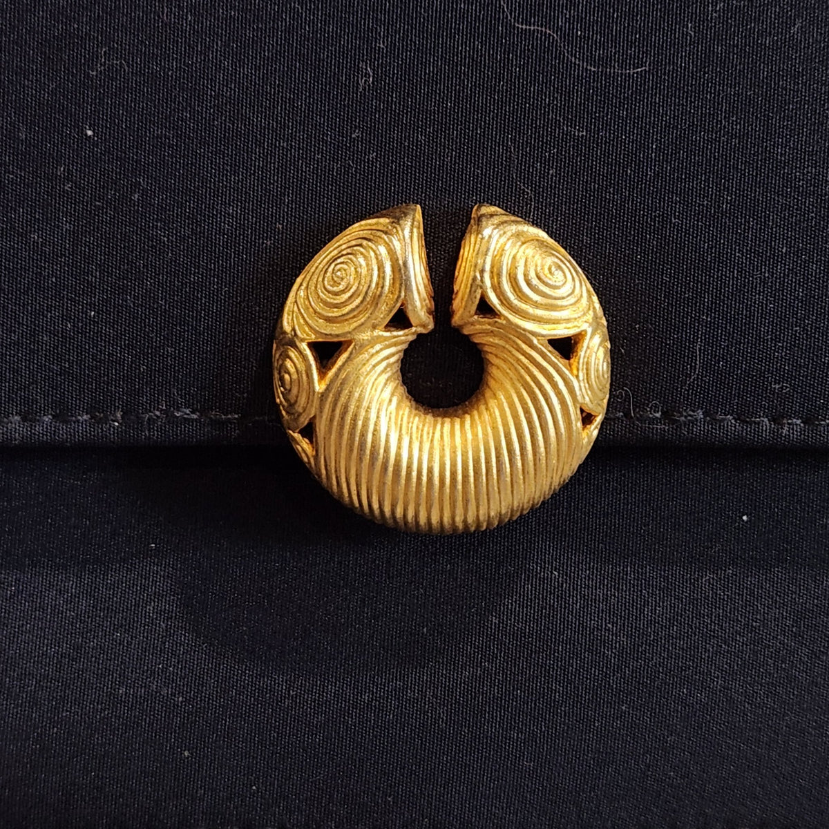 Original photo: close-up of the gold-tone circular sculptural clasp with spiral detailing