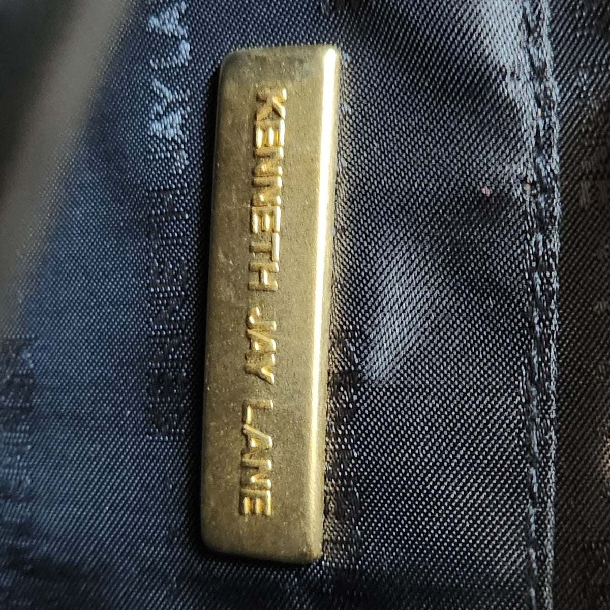 Original photo: close-up of the gold KENNETH JAY LANE designer plaque inside the bag
