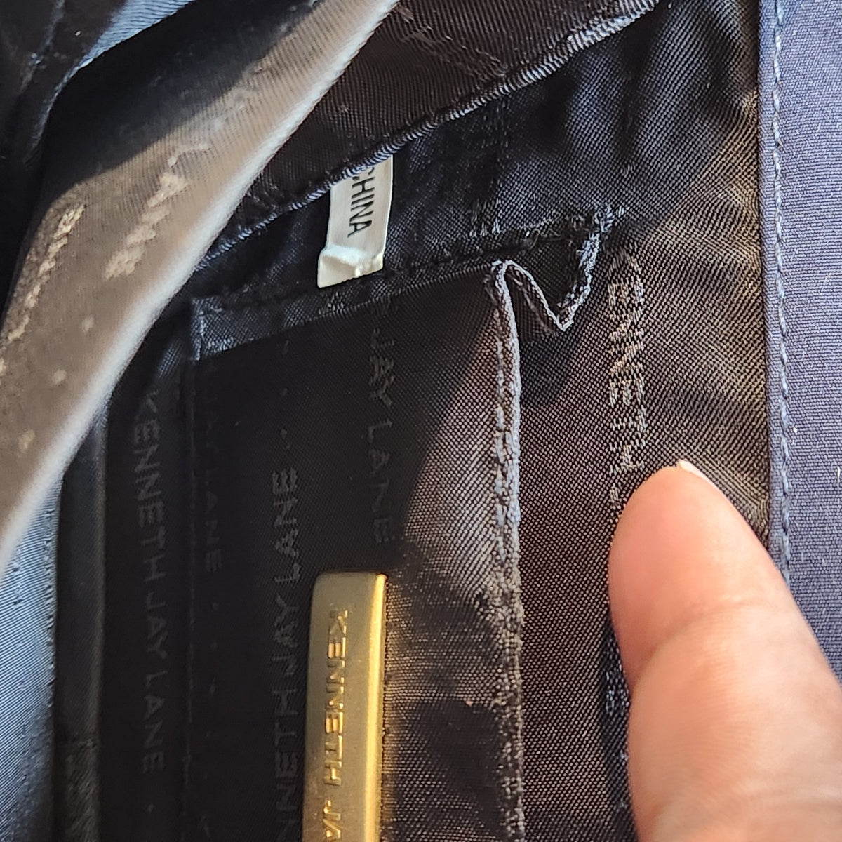 Original photo: interior of the bag showing the Kenneth Jay Lane branded lining, gold designer plaque, and small white tag