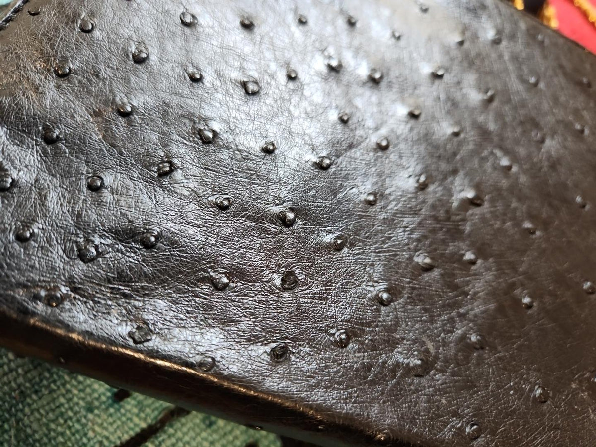 Close-up of the raised ostrich-like texture of vintage Beoni Lucia black leather evening bag, showing surface creasing and edge wear