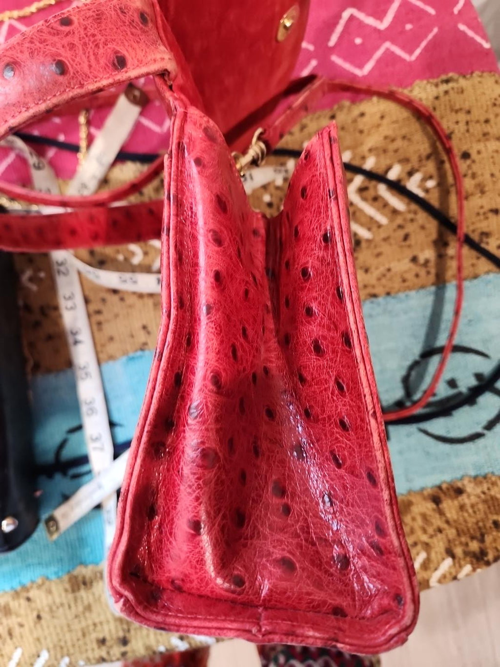 Side gusset detail of vintage Mike's Collection red ostrich-embossed leather mini handbag, open to show depth and structured shape