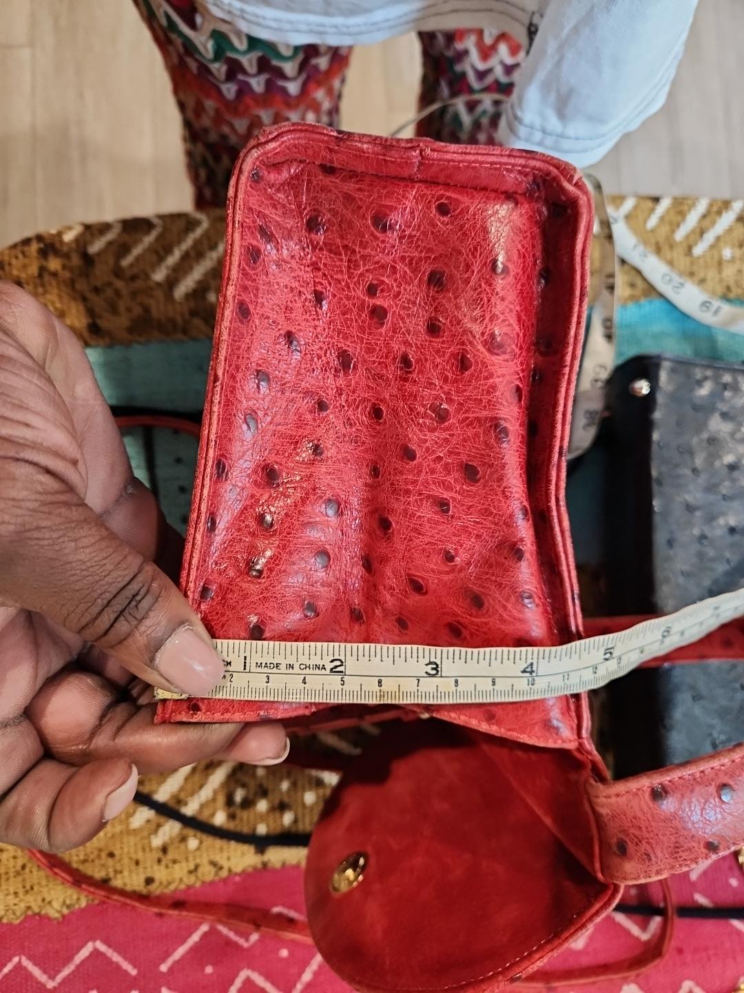 Depth measurement of vintage Mike's Collection red ostrich-embossed leather mini handbag base, tape measure showing approximately 5 inches