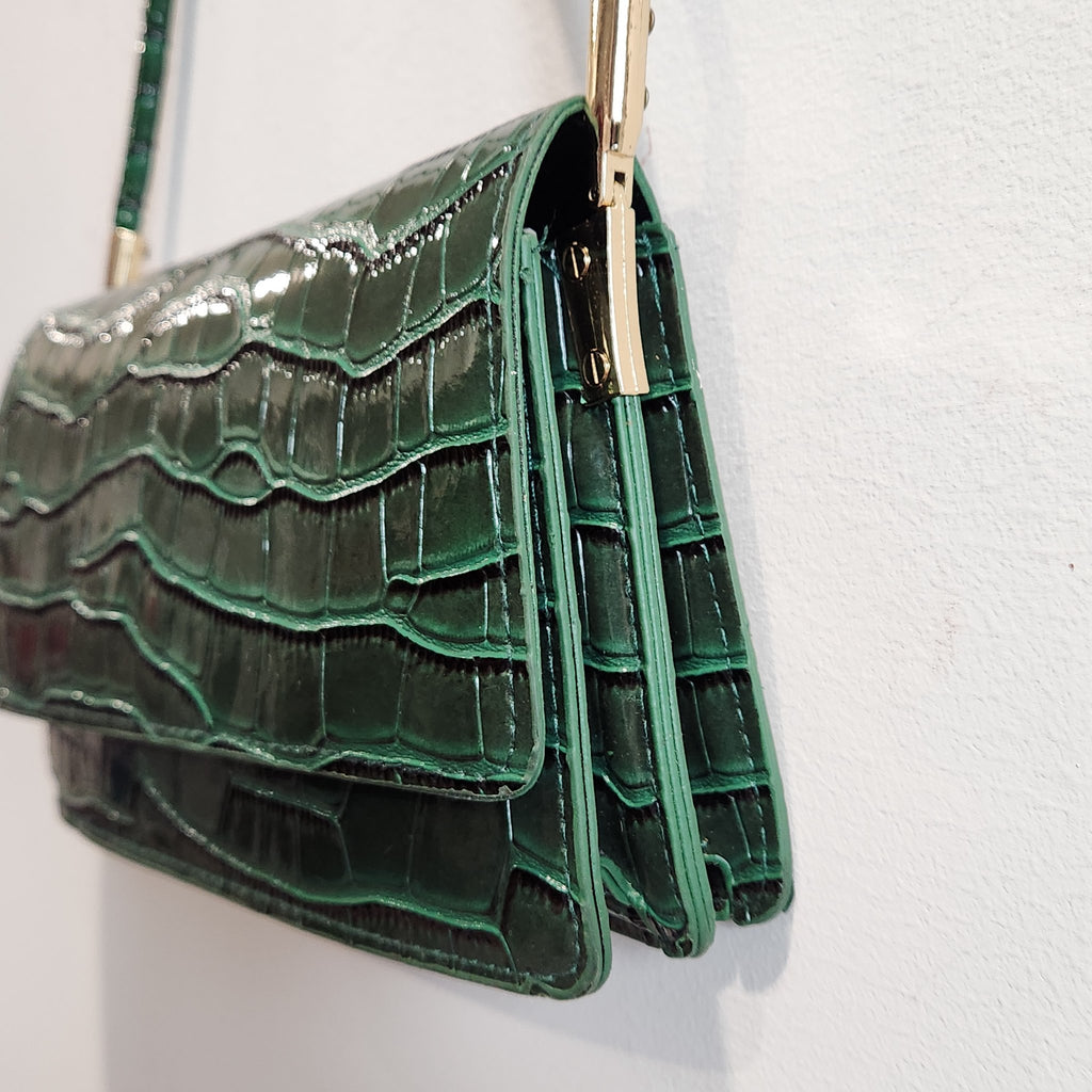 Side and gusset close-up of the forest green croc-embossed shoulder bag with gold-tone strap hardware