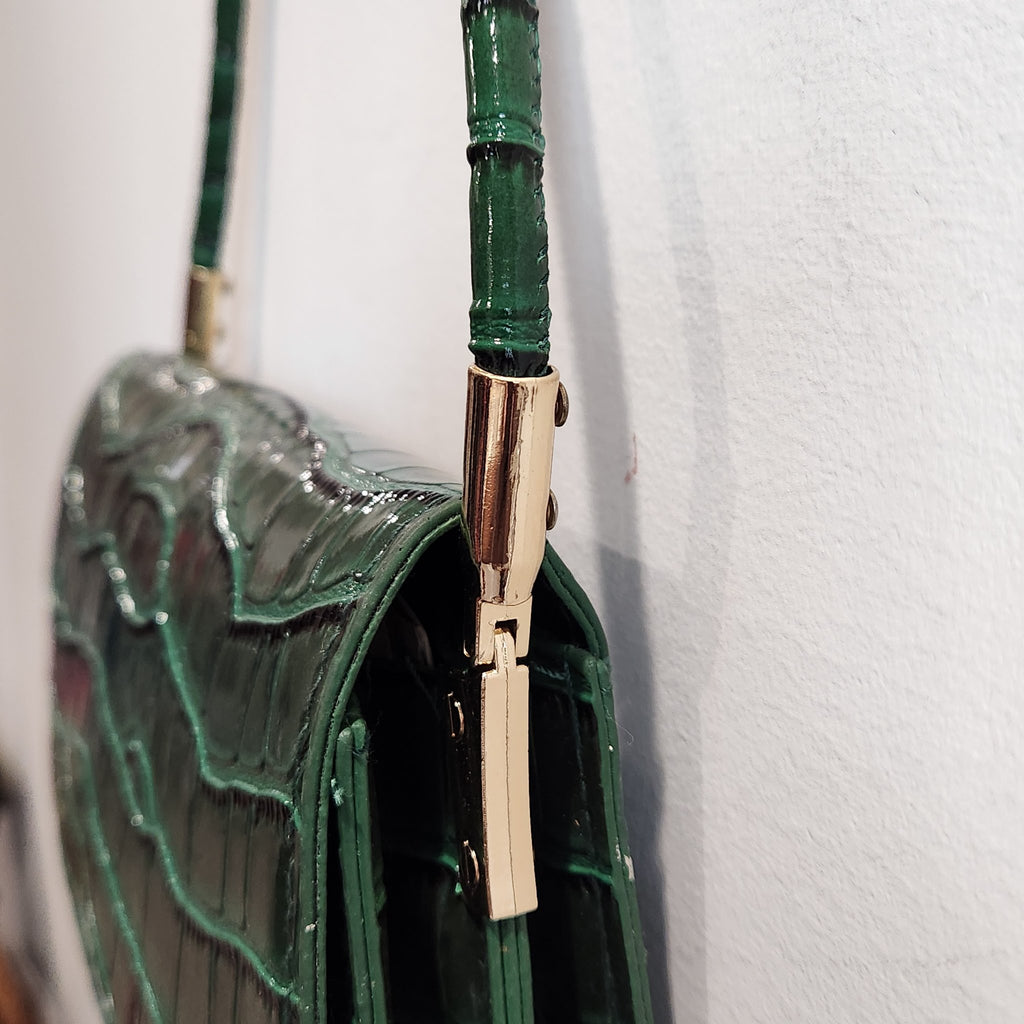 Close-up of the gold-tone strap hardware and segmented green shoulder strap