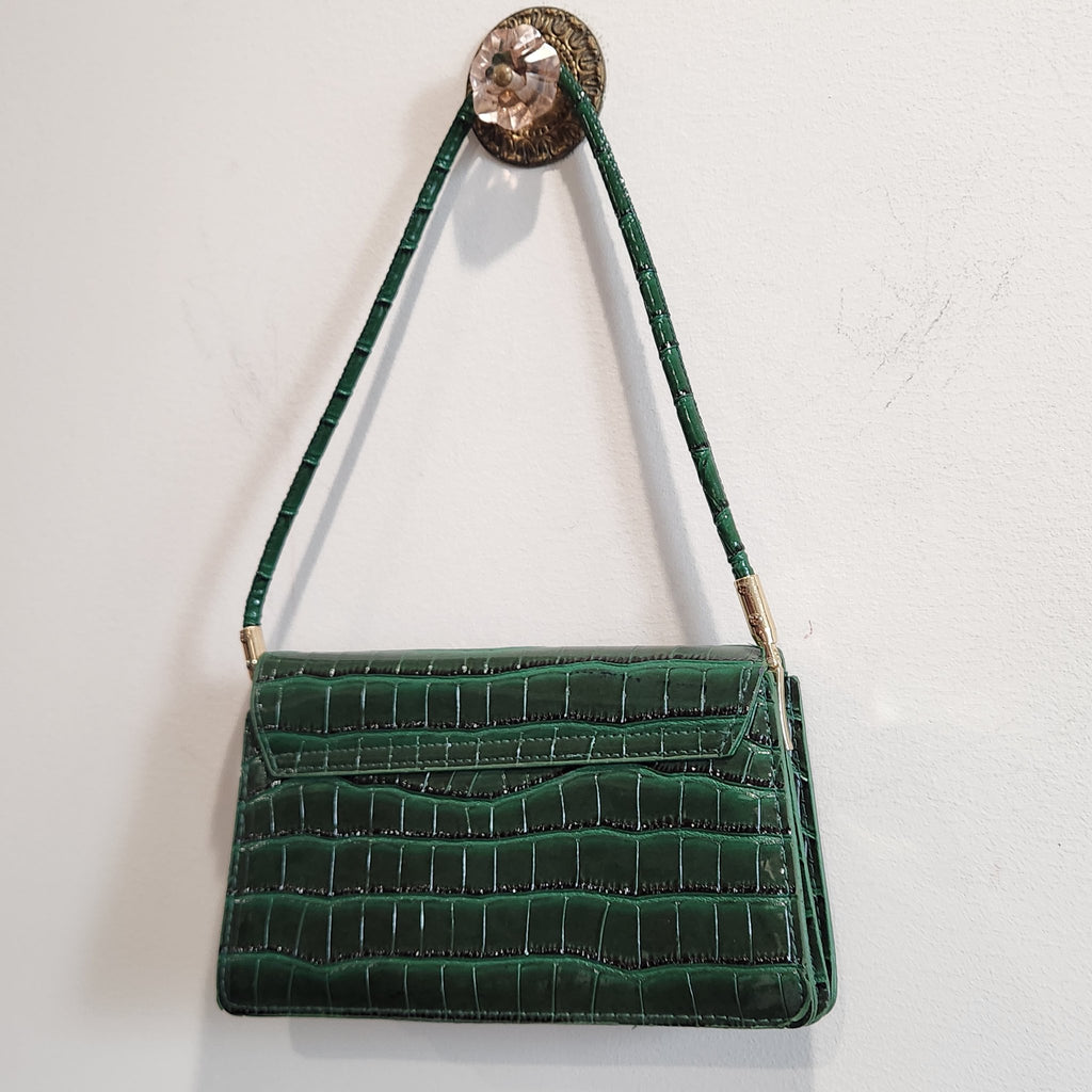 Back view of the forest green croc-embossed shoulder bag hanging, showing the flap back and shoulder strap