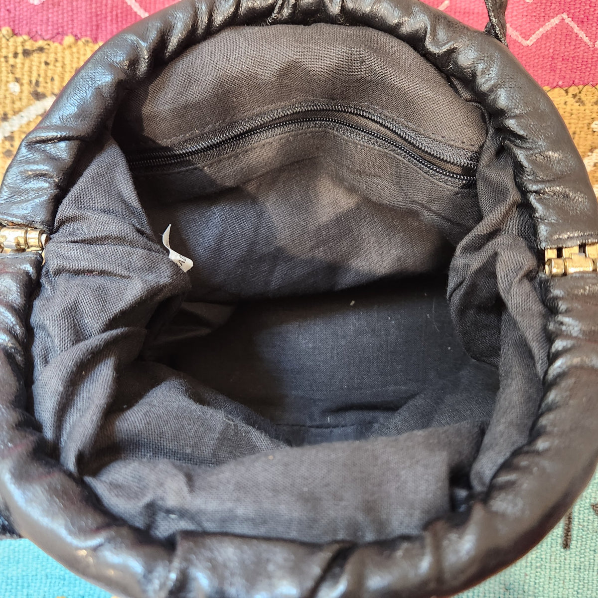 Original photo: close-up of the interior showing the black fabric lining, zippered pocket and gold-tone hinge hardware