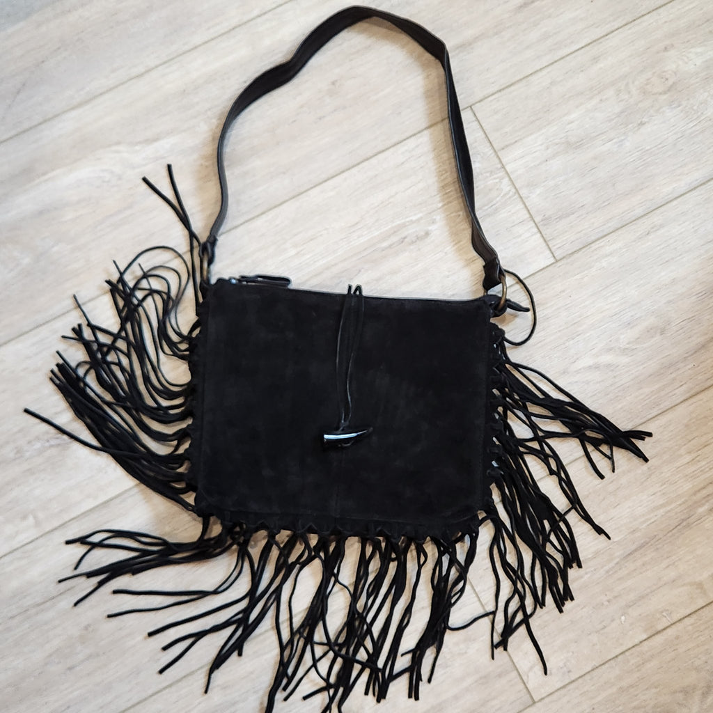 Original photo: vintage EGO black suede fringe shoulder bag, front view on a light wood floor, toggle closure and fringe