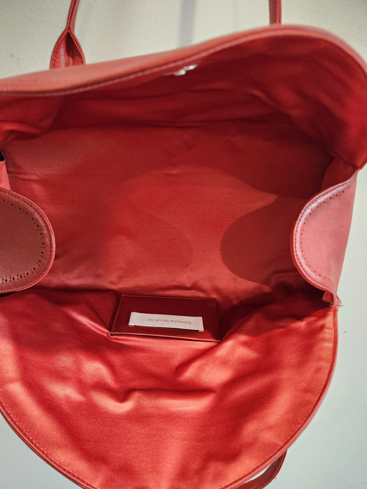 Interior lining and designer label of vintage Robinson Valentine brick-red leather barrel shoulder bag