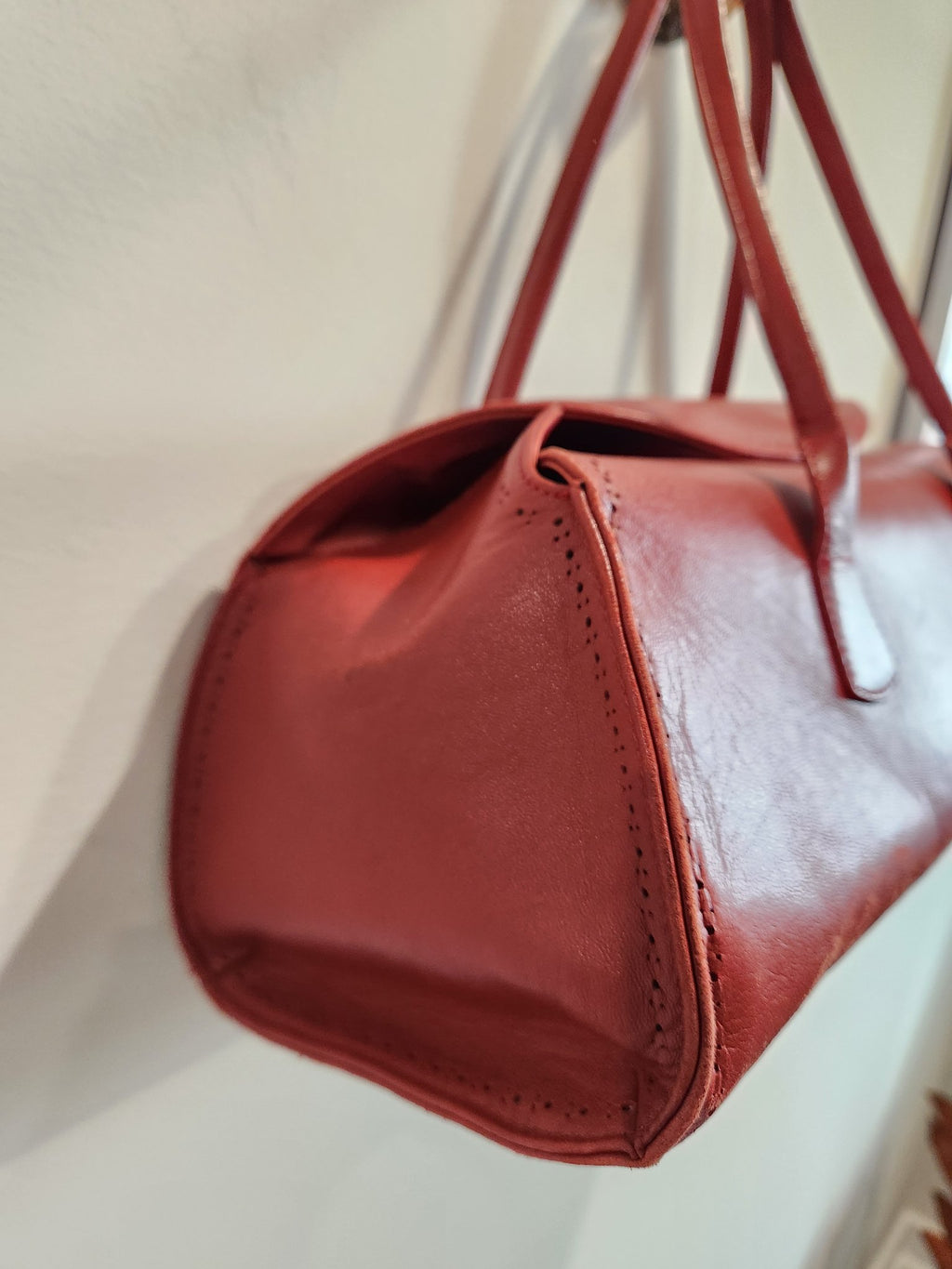 Close-up of the end panel of vintage Robinson Valentine brick-red leather barrel shoulder bag