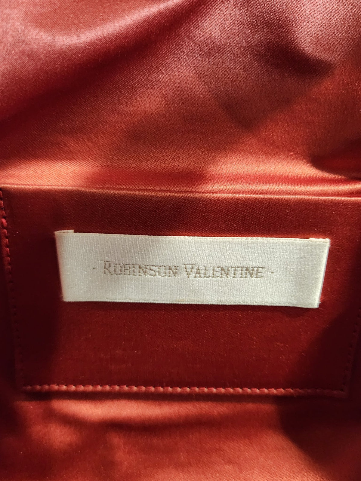 Close-up of the designer label inside vintage Robinson Valentine brick-red leather barrel shoulder bag