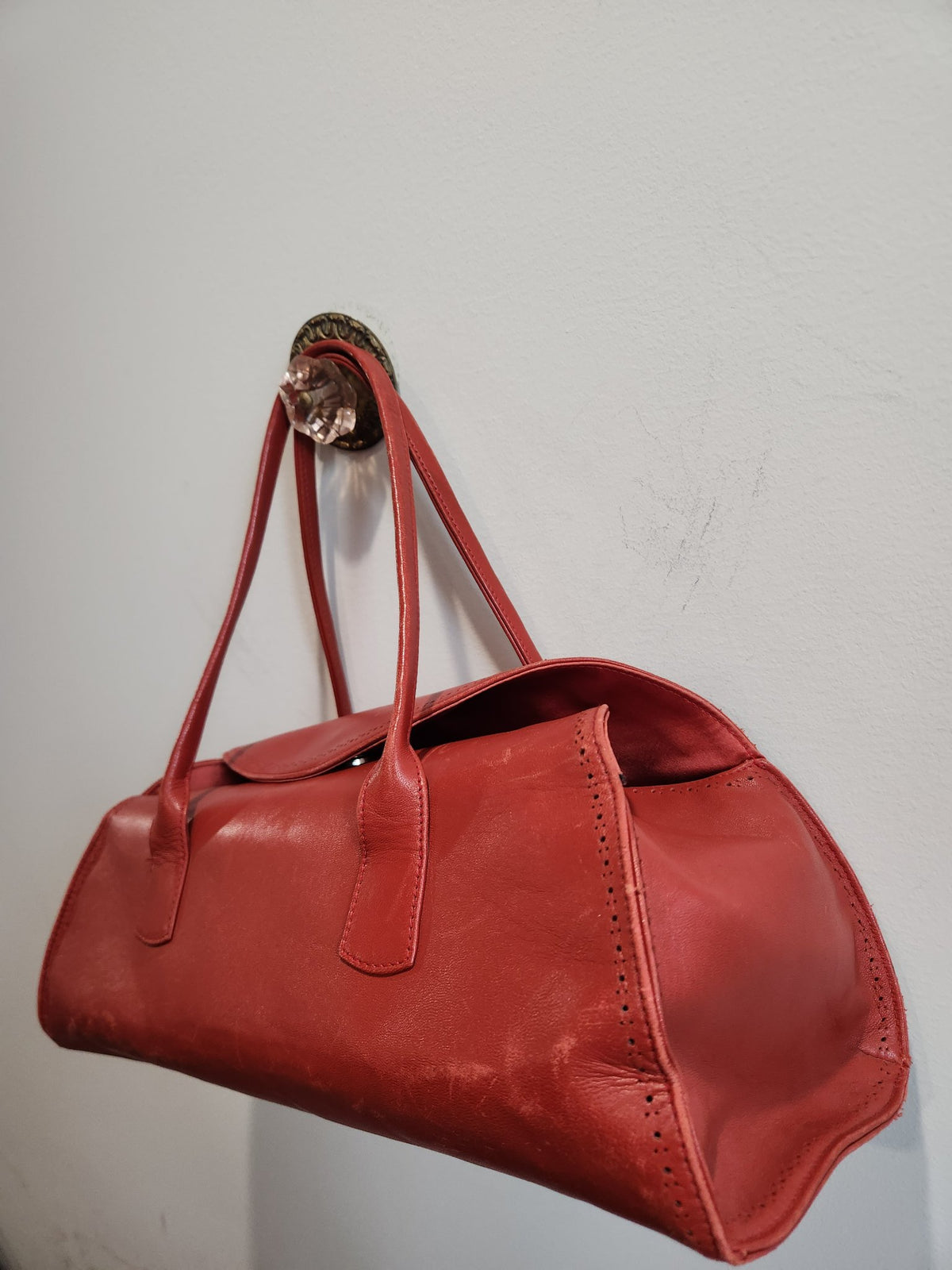 Side angle view of vintage Robinson Valentine brick-red leather barrel shoulder bag, showing barrel silhouette and wear