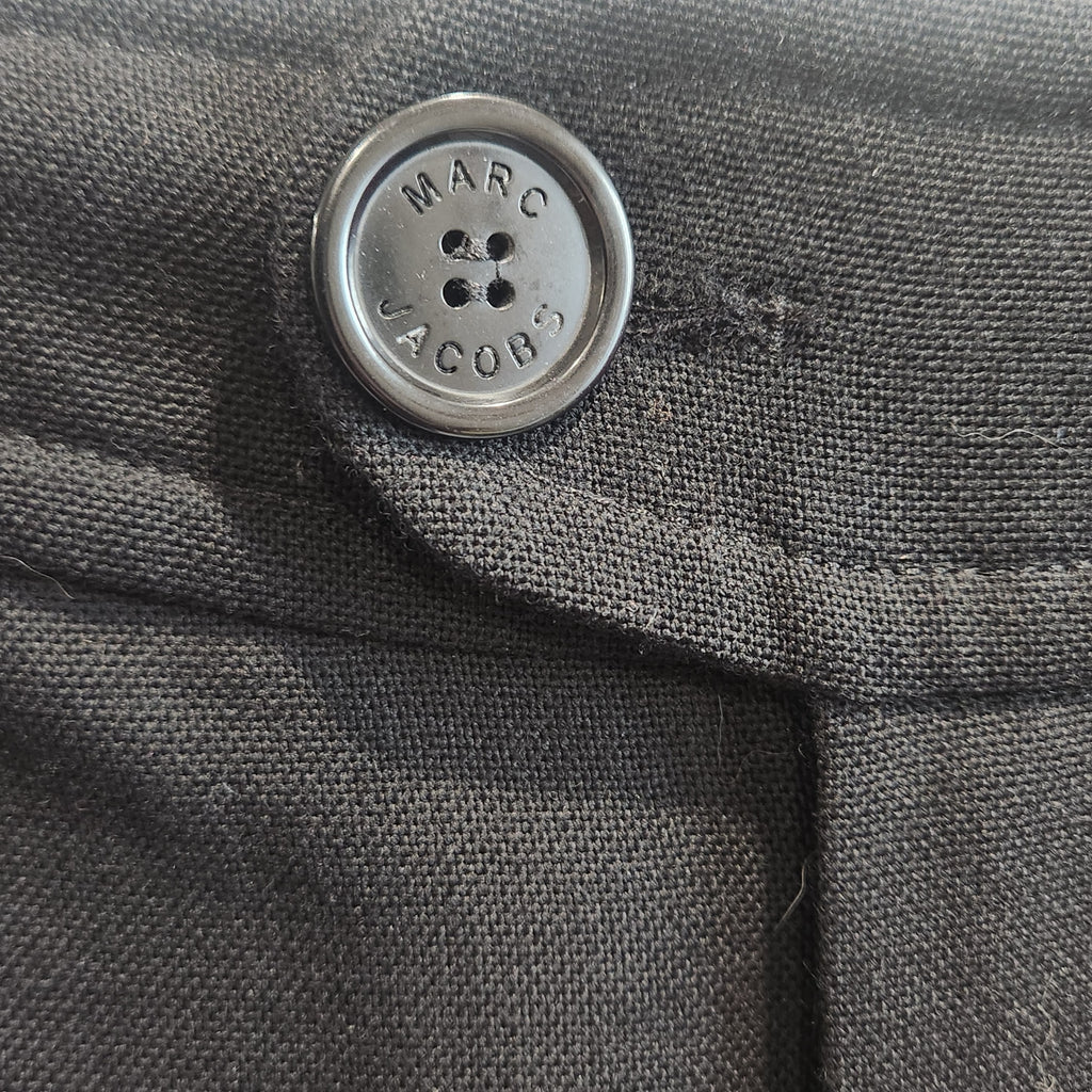 Close-up of a black wool trouser button featuring the Lucille Golden Vintage, LLC Marc Jacobs logo engraving.