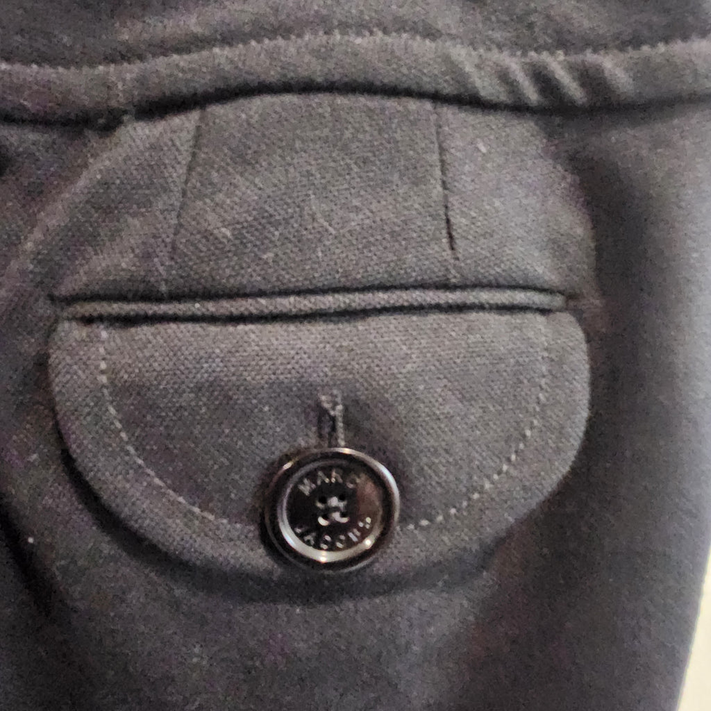Close-up of a black wool trouser pocket with a button flap featuring the Lucille Golden Vintage, LLC Marc Jacobs logo