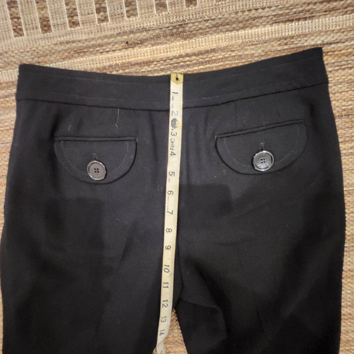 Lucille Golden Vintage, LLC black wool trousers with button-flap back pockets and measuring tape for size reference