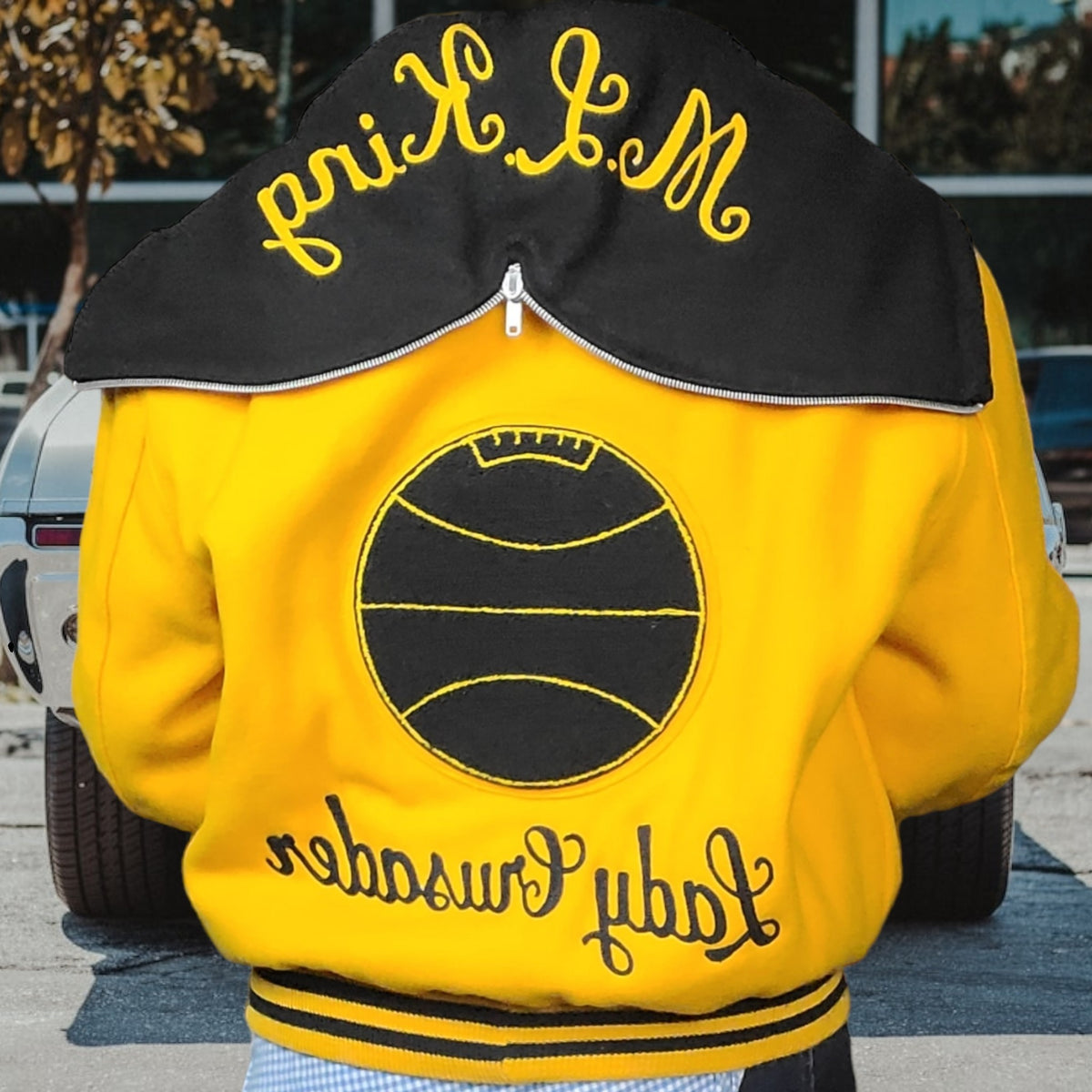 Lucille Golden Vintage, LLC 1990s DeLong varsity jacket in gold wool with black basketball patch and ML King hood
