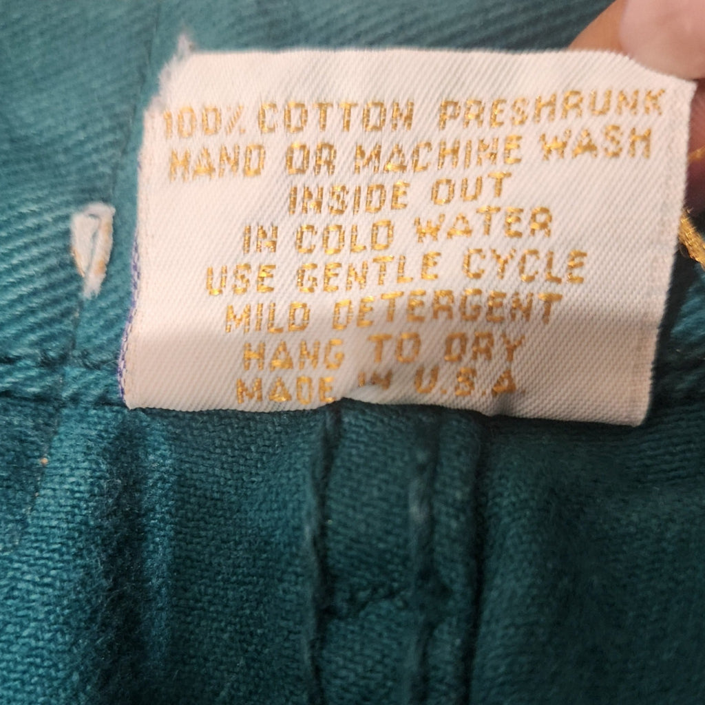 Lucille Golden Vintage, LLC care label on teal cotton Monique Jeans shorts with gold text detailing