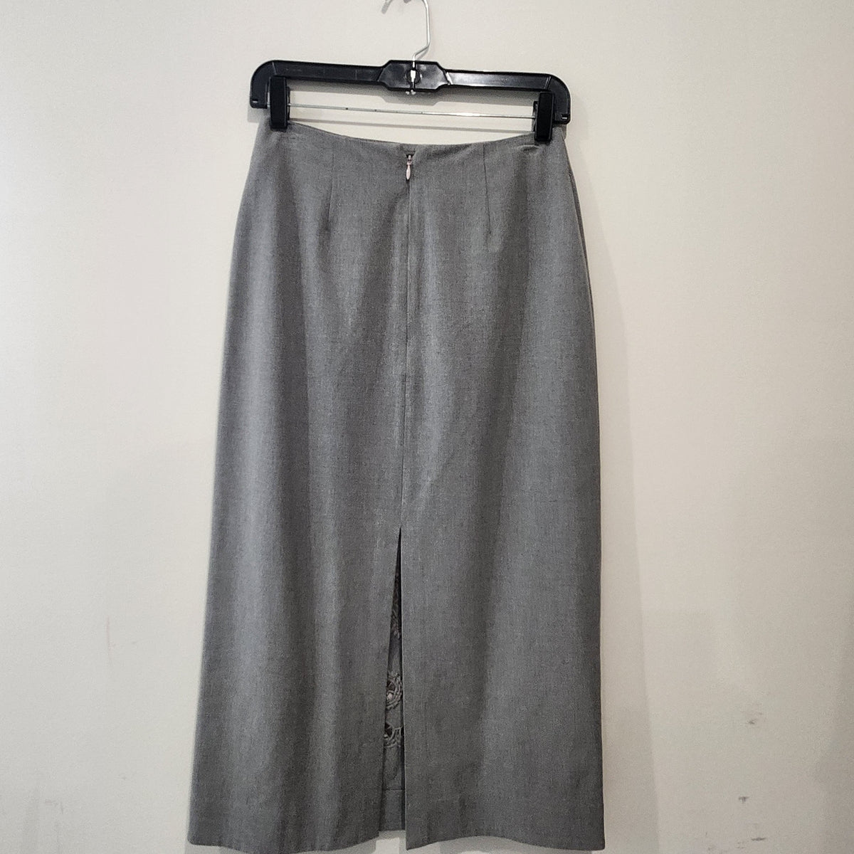 Lucille Golden Vintage, LLC grey midi skirt with back slit and circular laser-cut embroidery detail on a hanger.
