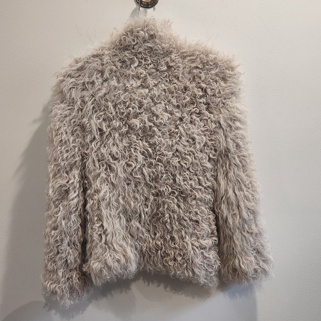 Lucille Golden Vintage, LLC IRO beige curly lamb fur jacket with a shaggy texture hanging against a plain wall.