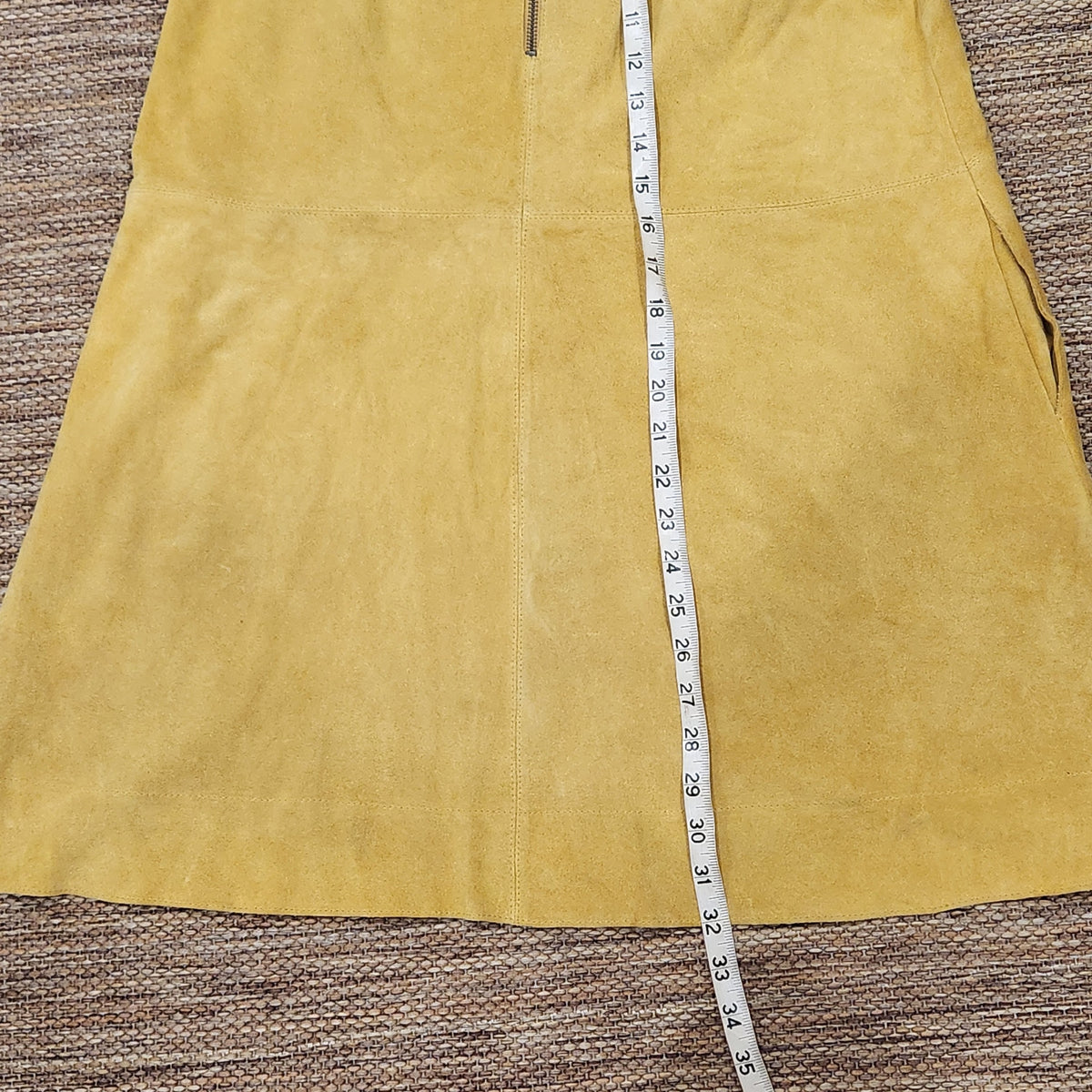 Lucille Golden Vintage, LLC mustard yellow suede mini dress with measuring tape showing length on a textured surface