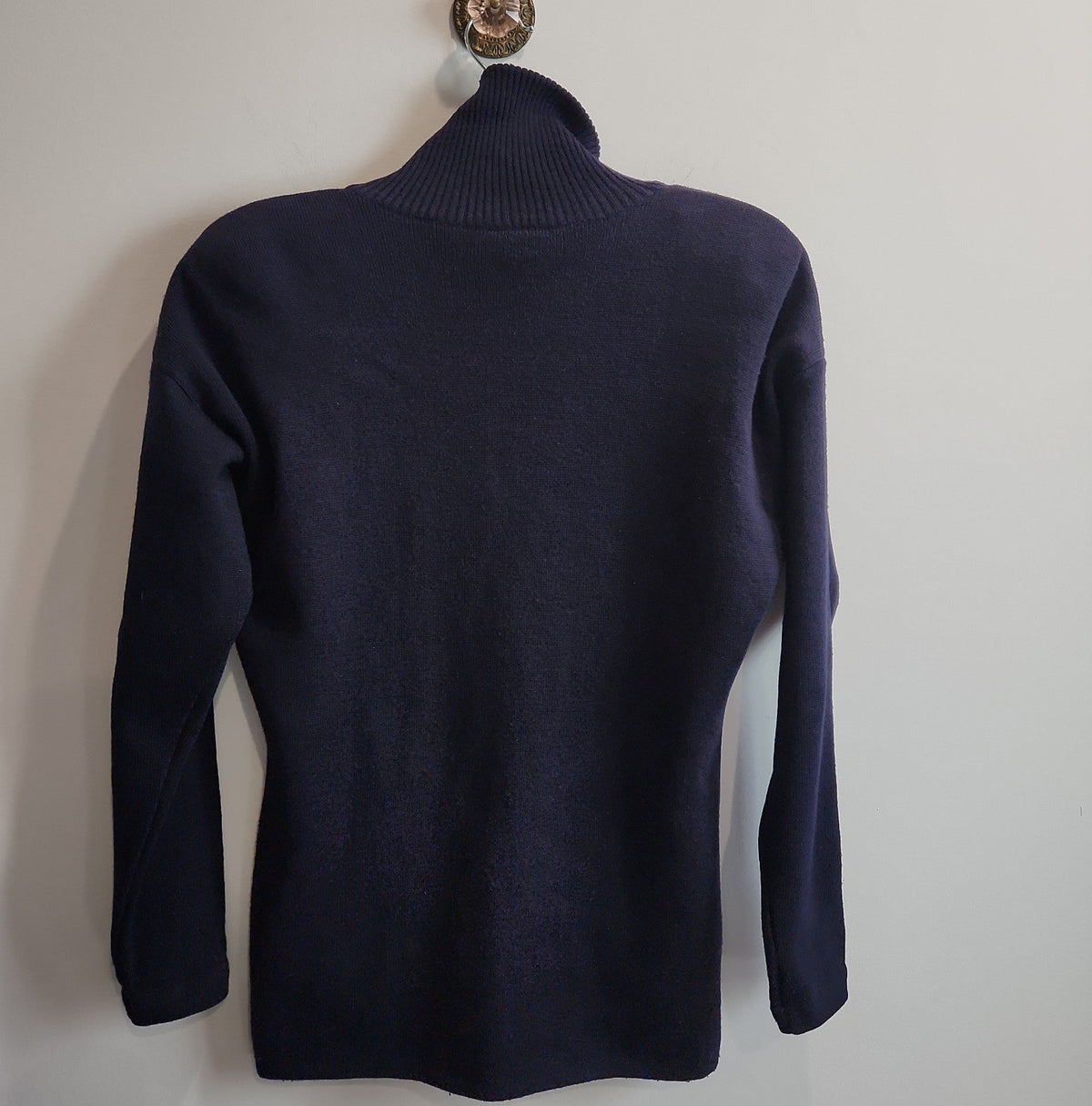 Lucille Golden Vintage, LLC navy blue mock neck long sleeve knit sweater hanging on a wall hook