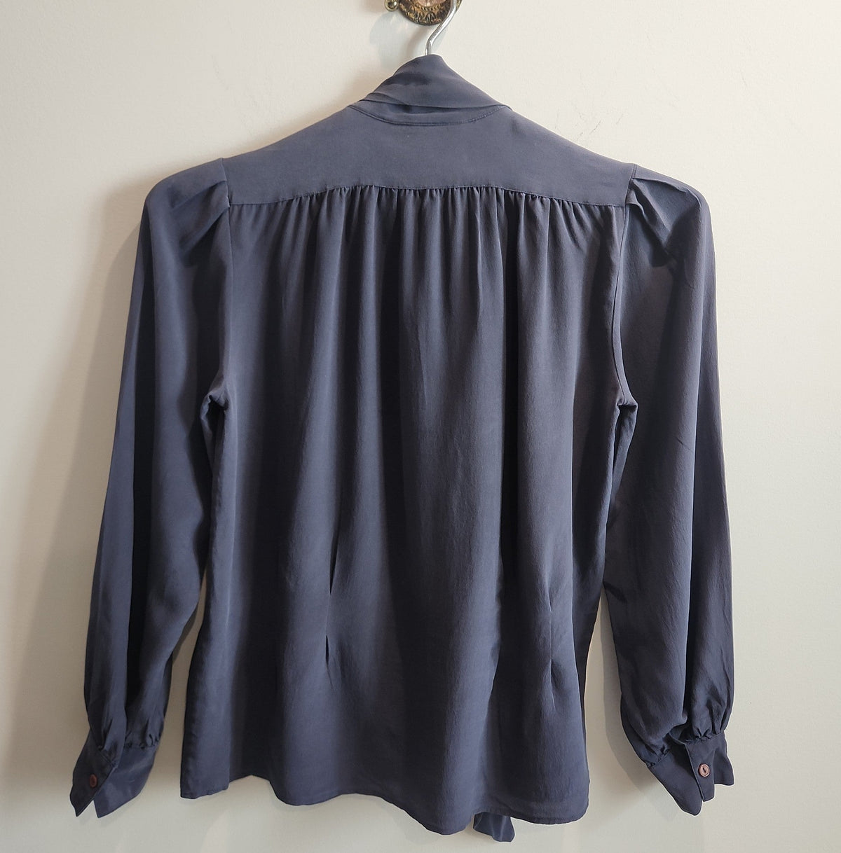 Back view of a Lucille Golden Vintage, LLC slate-grey long sleeve blouse with gathered shoulders and buttoned cuffs.