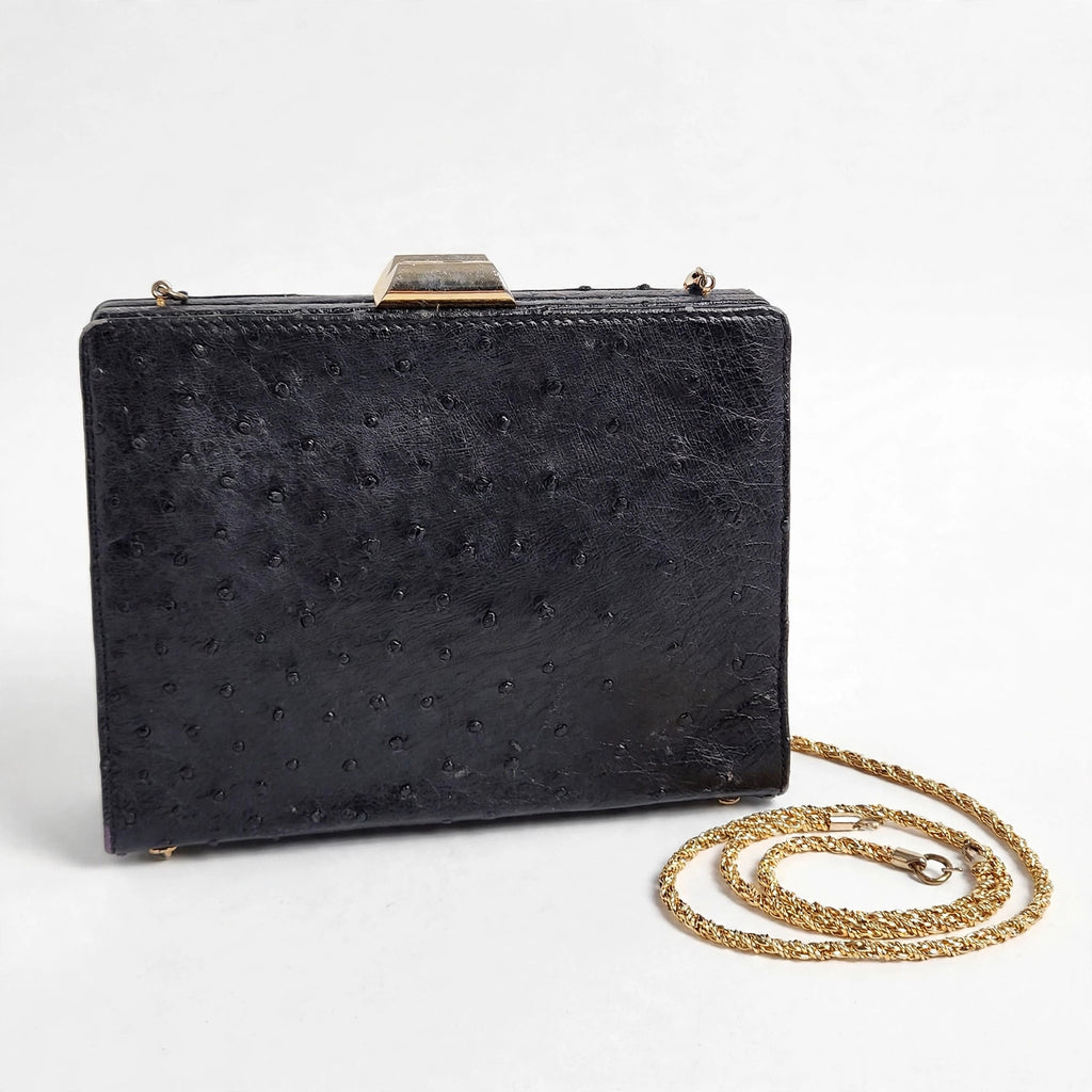 Front view of vintage Beoni Lucia black ostrich-textured leather evening bag on a white background, with braided gold-tone chain strap arranged beside it