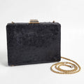 Front view of vintage Beoni Lucia black ostrich-textured leather evening bag on a white background, with braided gold-tone chain strap arranged beside it