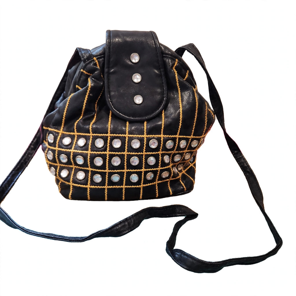 Black embellished bucket shoulder bag on a white background, front view, gold grid embroidery and crystal-style studs, long black shoulder strap