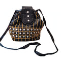 Black embellished bucket shoulder bag on a white background, front view, gold grid embroidery and crystal-style studs, long black shoulder strap