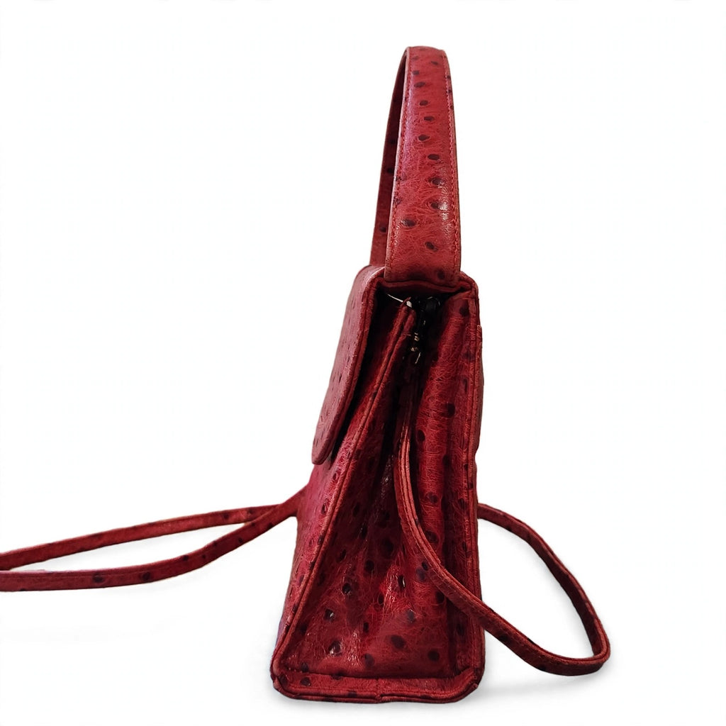 Side profile of vintage Mike's Collection red ostrich-embossed leather mini handbag on a white background, showing the gusset and structured depth