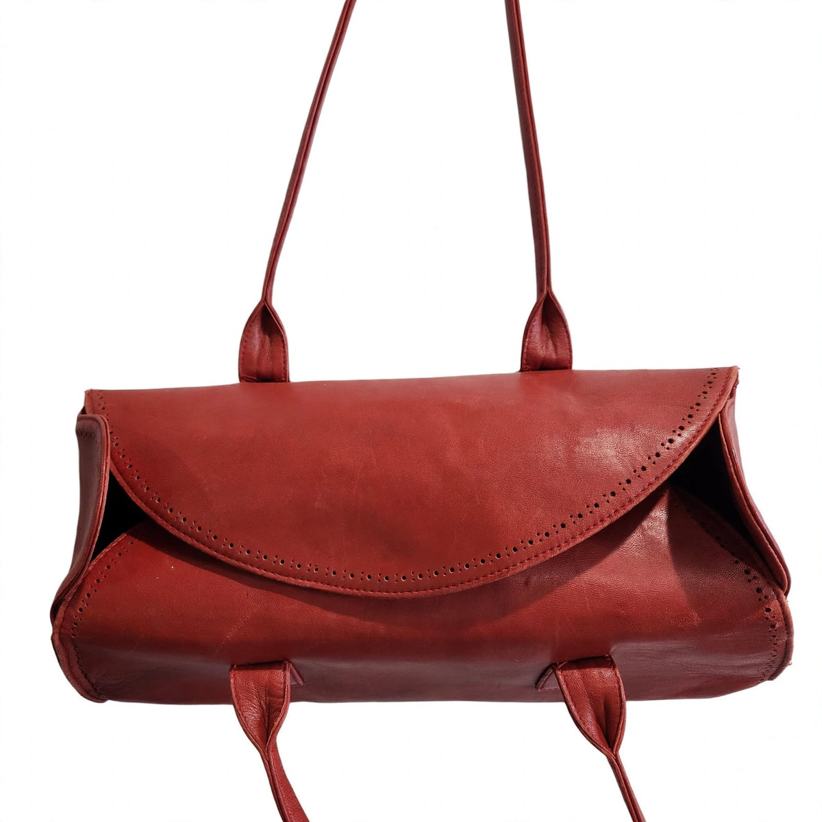 Front flap detail of vintage Robinson Valentine brick-red leather barrel shoulder bag with perforated leather detailing, on a white background
